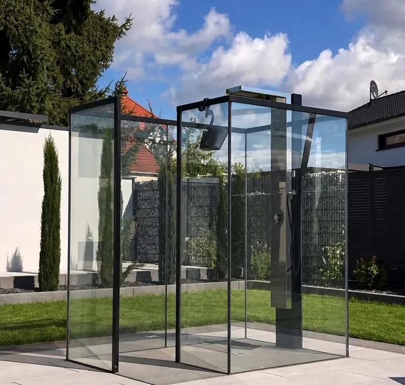 Staklena konstrukcija sa crnim profilima u dvorištu